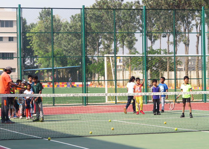Students participating in a tennis training session at NewAge World School's sports facility.
